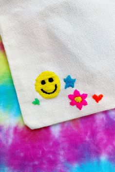 a tie dye shirt with a smiley face embroidered on it