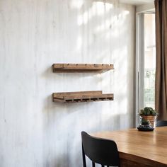 two wooden shelves on the wall above a dining room table with chairs and a potted plant