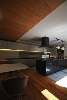 an empty kitchen with wooden floors and black counter tops, along with modern lighting fixtures