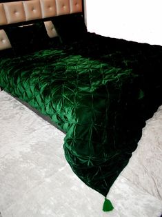 a bed with a green comforter on top of it