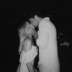 black and white photograph of two people kissing in the dark, one woman is wearing a white dress