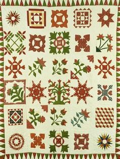 a white quilt with red and green designs on the front, along with an orange border