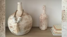 two vases sitting next to each other on top of a wooden shelf with books