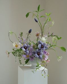 a white vase filled with purple and white flowers