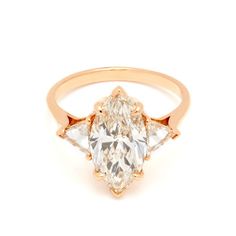 an oval diamond ring with three pear shaped diamonds on the band and side stones in rose gold