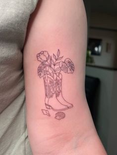 a woman's arm with a tattoo on it that has a boot and flowers in it