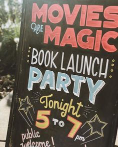 a sign advertising movies are magic and book launch party