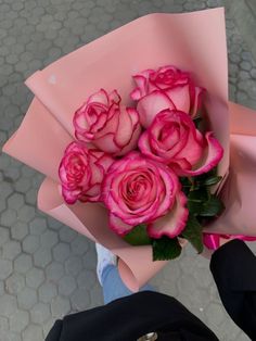 a person holding a bouquet of pink roses