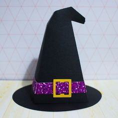 a black witch hat with purple sequins and a yellow buckle on the front