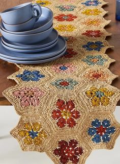 a crocheted table runner with plates and cups on it