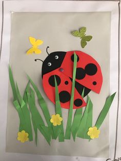 a ladybug paper craft with grass and butterflies