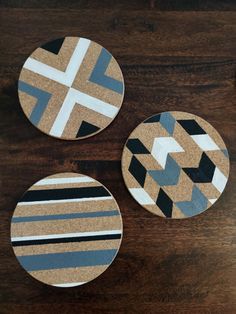 three coasters made out of cork with different patterns on them, sitting on a wooden table