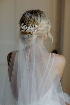 the back of a bride's head with a veil over her shoulder and flowers on it