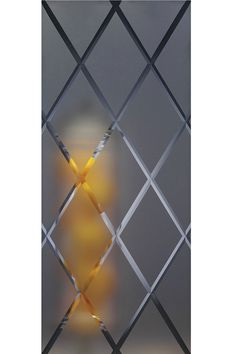 the reflection of a yellow light in a glass window with metal bars on it's sides