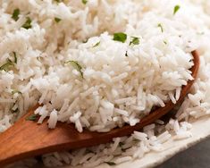 white rice in a wooden spoon with parsley on top