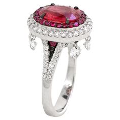 a ring with a large red stone surrounded by smaller white and pink stones in the center