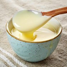 a wooden spoon in a blue bowl filled with yogurt on a tablecloth