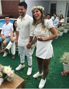 a man and woman standing next to each other in front of a pool surrounded by people