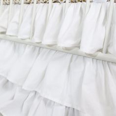 a baby crib with white ruffles hanging from it's sides