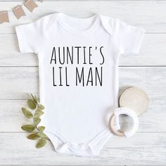 Aunties Little Man Baby Bodysuit, Aunt Pregnancy Announcement, Baby Gift From Aunt, Baby Shower Gift Boy, Baby Boy Outfit, Baby Boy Clothes 💗 Welcome to The MintedWildflower Etsy Shop! DESCRIPTION: An adorable baby bodysuit with softness that is perfect for an infant's sensitive, smooth skin. Durable print will survive the very first adventures of your little explorer. Celebrate your bundle of sunshine with this sweet bodysuit. This adorable piece is the perfect light layer for a baby. This pro Personalized White Bodysuit For First Birthday, White Personalized Bodysuit For First Birthday, White Bodysuit With Name Print For First Birthday, Aunt Onesie Boy, Onsies Ideas Boy, Baby Boy Onesies Vinyl, Auntie Baby Clothes, Aunt Baby Clothes, Boy Onsies