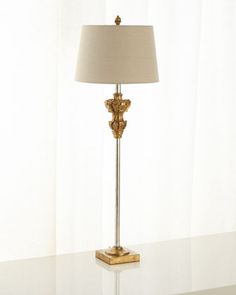 a lamp that is sitting on top of a table in front of a white curtain