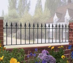 a black iron fence with flowers in the foreground