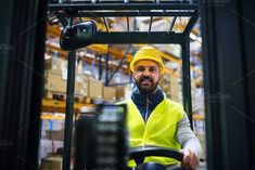 a man in a yellow safety vest is driving a forklift and looking at the camera