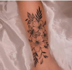 a woman's foot with flowers and leaves tattooed on the side of her leg