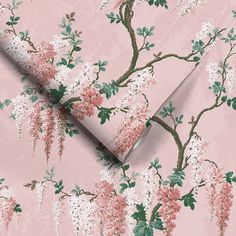 a pink wallpaper with white flowers and green leaves on the top of it, next to a large roll of paper