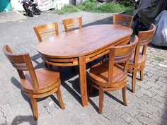 a wooden table with six chairs around it on a brick floor next to a motor scooter