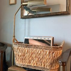 a wicker basket with cd's in it sits on a table next to a mirror