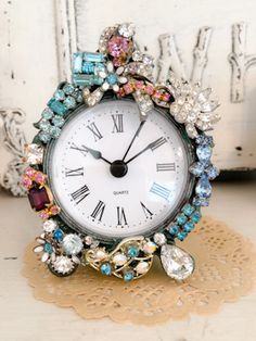 an ornate clock with jewels on it sitting on a doily