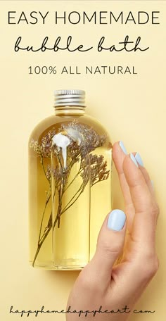 a woman's hand holding a bottle of homemade bubble bath with flowers in it and the words, easy homemade bubble bath 100 % all natural