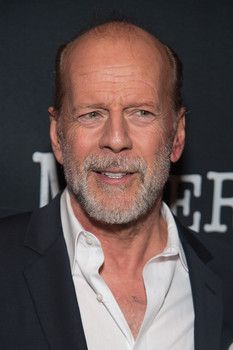 an older man wearing a black suit and white shirt smiles at the camera while standing in front of a dark background