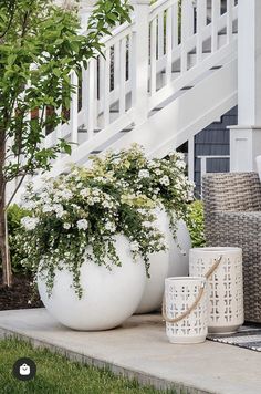 two large white vases sitting next to each other on the ground in front of a house