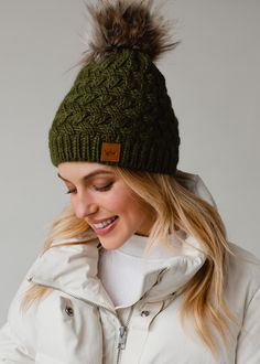 a woman wearing a green hat with a fur pom