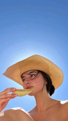 a woman in a straw hat eating a hot dog