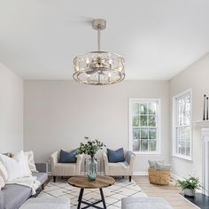 a living room filled with furniture and a chandelier hanging from the ceiling over a fire place