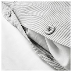 black and white photograph of buttoned shirt with collar on bedding set, closeup