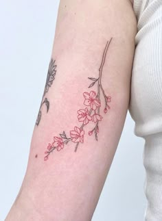 a woman's arm with flowers and leaves on the left side of her arm