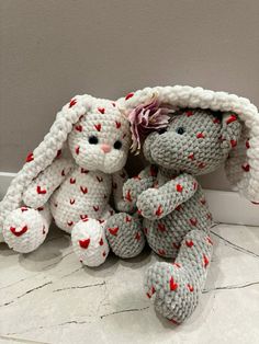 two crocheted stuffed animals sitting next to each other on the floor in front of a wall