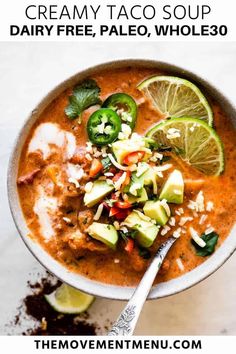 a bowl of creamy taco soup with limes, avocado and cilantro