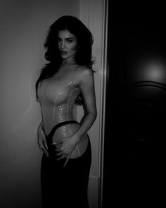 a woman standing in front of a door with her hands on her hips and wearing a corset