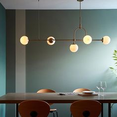 a dining room table with chairs and lights hanging from the ceiling