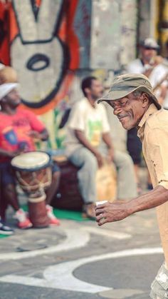 an old man walking down the street with his hand in his pocket and people sitting around him