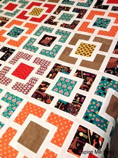 a close up of a quilt on a bed with an orange and blue blanket behind it