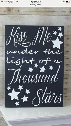 a sign that says kiss me under the light of a thousand stars with white stars on it