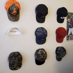 several hats are hanging on the wall with baseball caps attached to it's sides