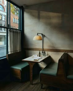 a room with two chairs and a table in front of a window that has a lamp on it