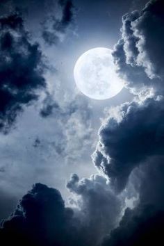 the moon is shining brightly in the cloudy sky with dark clouds and bright blue hues